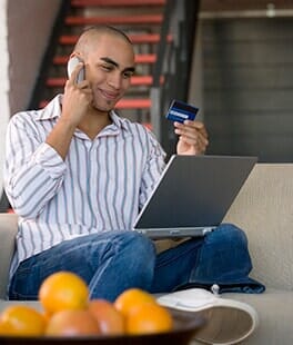 Man on phone reading credit card with laptop